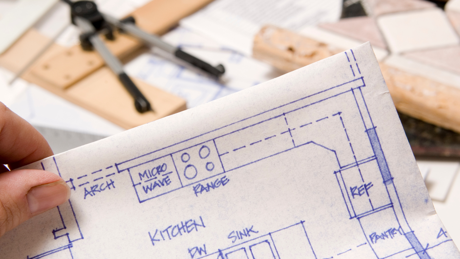 A person is holding a blueprint of a kitchen