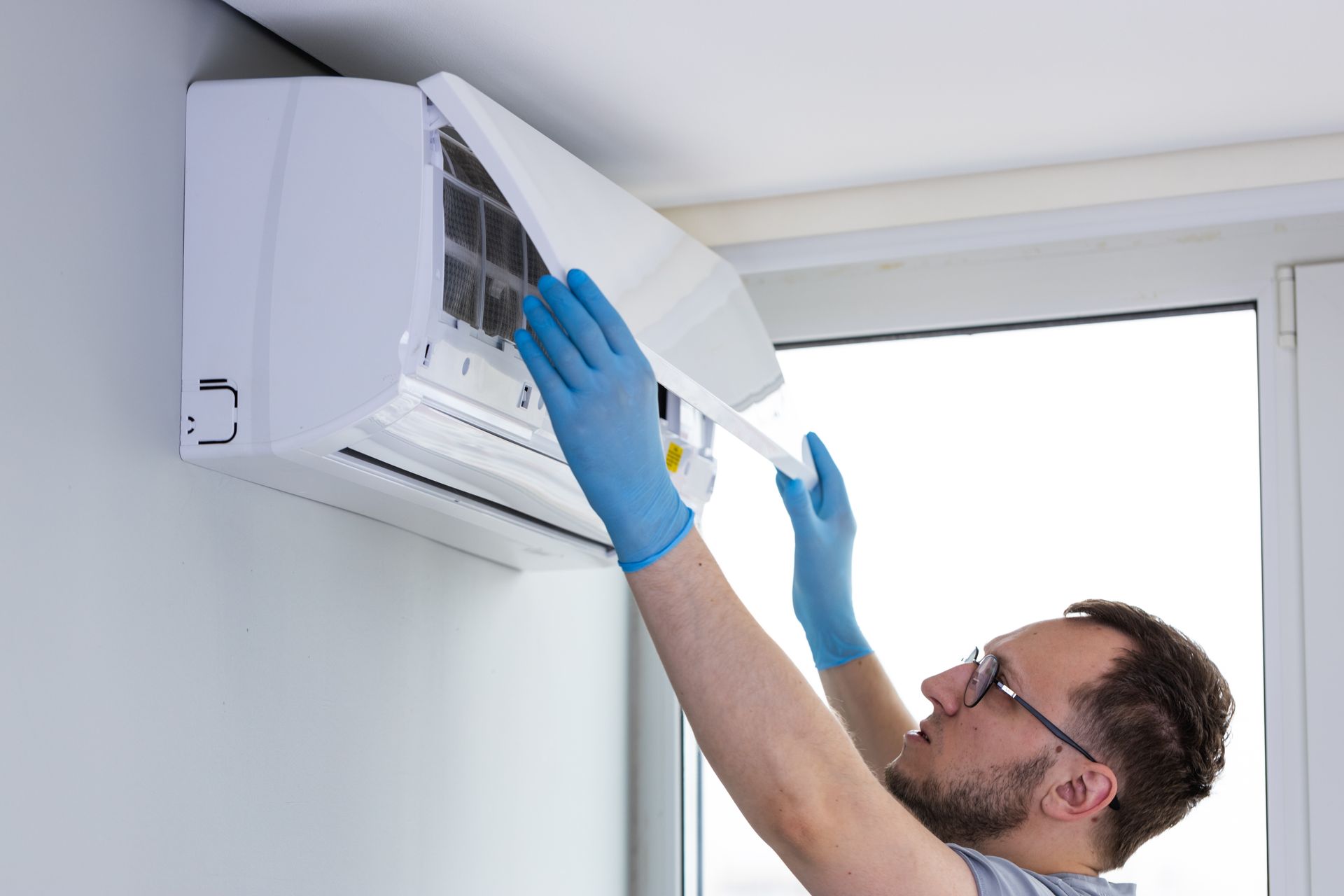 A technician opening an air conditioner unit to inspect and clean internal components.