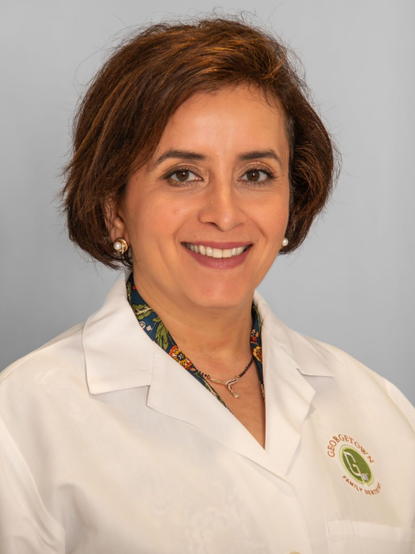 Woman in white lab coat smiling, likely a healthcare professional.