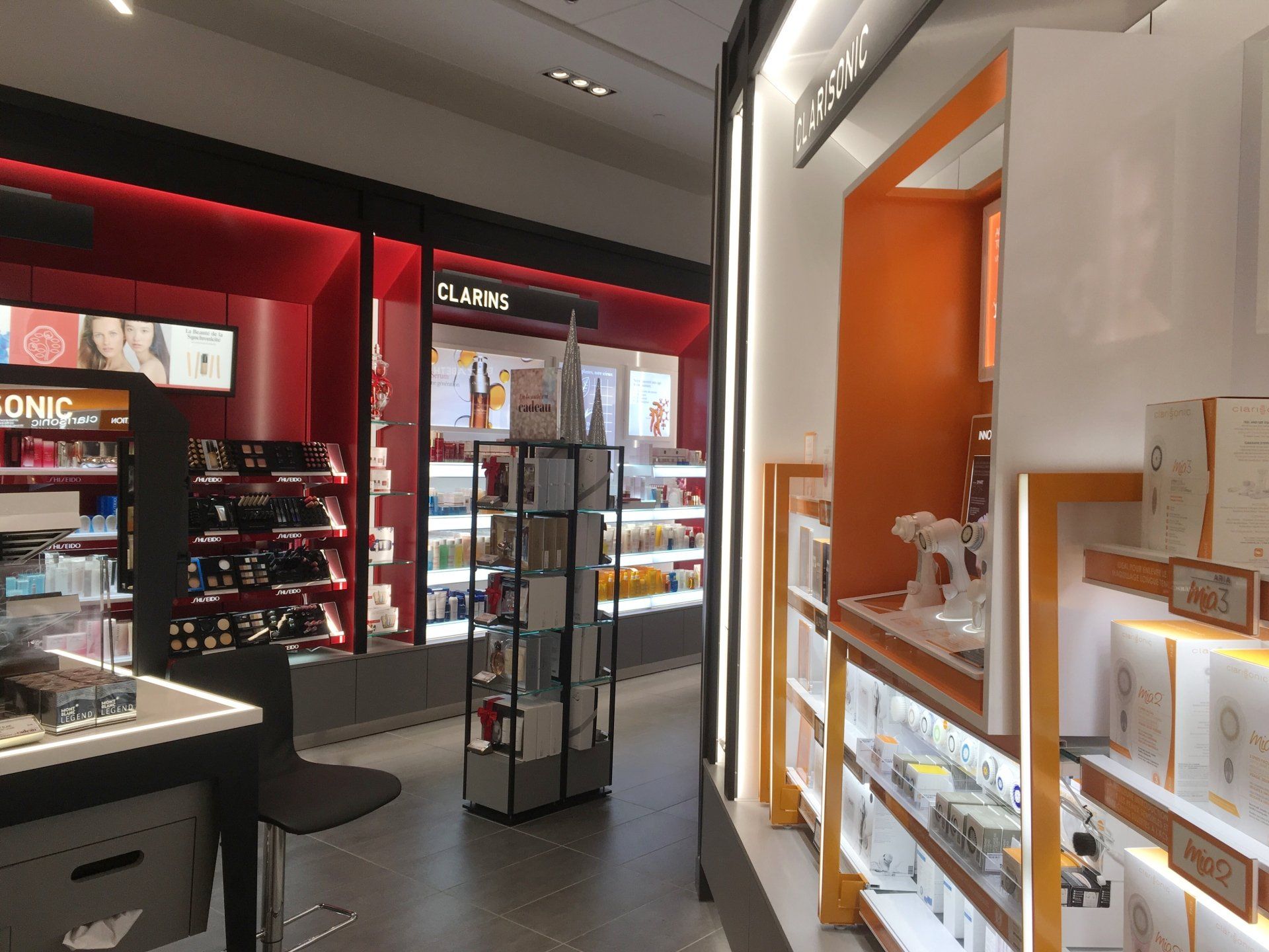 Intérieur d'un magasin de cosmétiques avec divers présentoirs de produits et un éclairage vif.