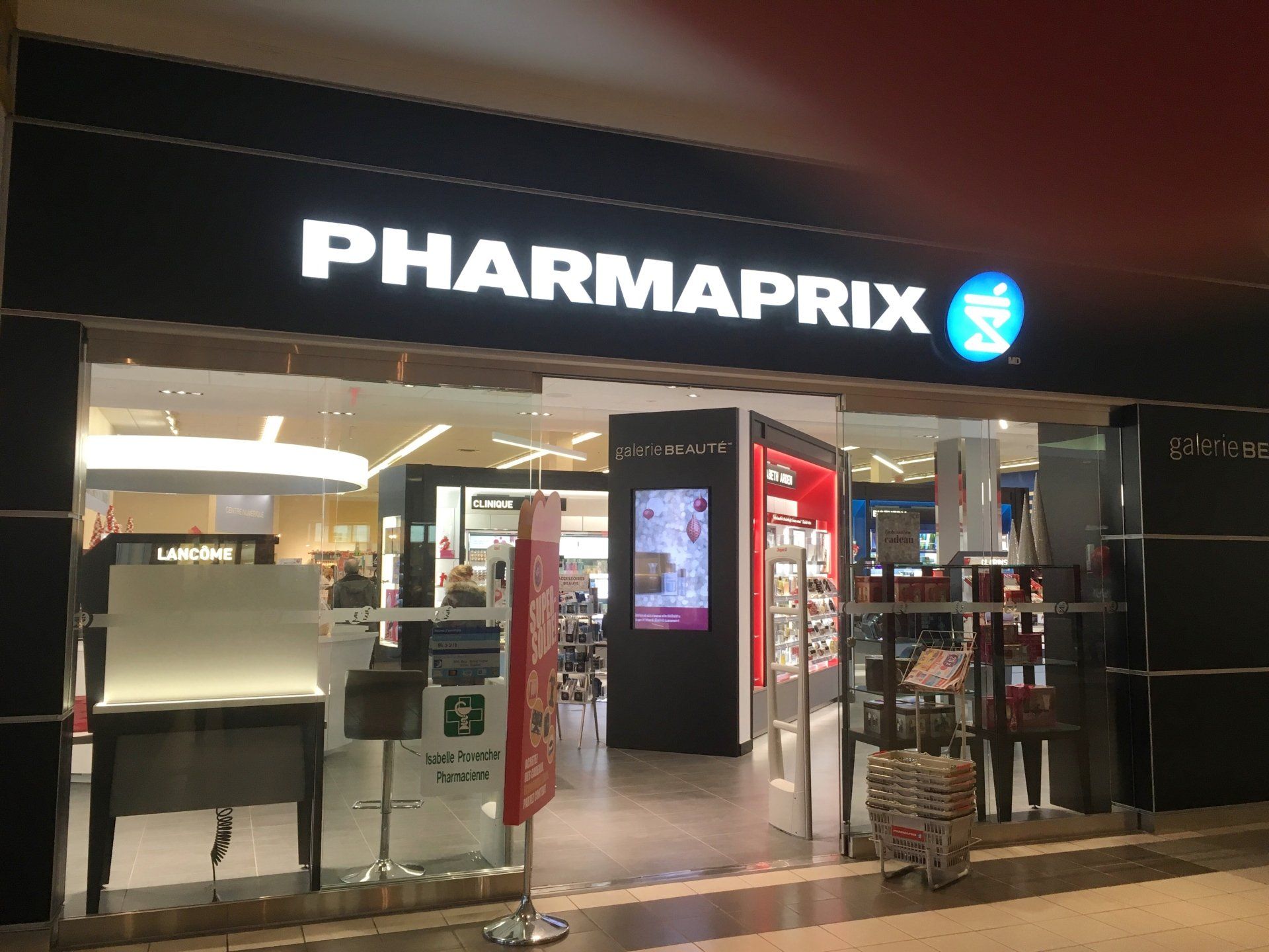 Façade de magasin Pharmaprix avec enseigne lumineuse ; entrée vitrée, présentoir de maquillage, signalétique rouge.