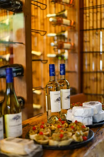 Garrafas de vinho e uma travessa de aperitivos sobre uma mesa em um ambiente acolhedor de restaurante.