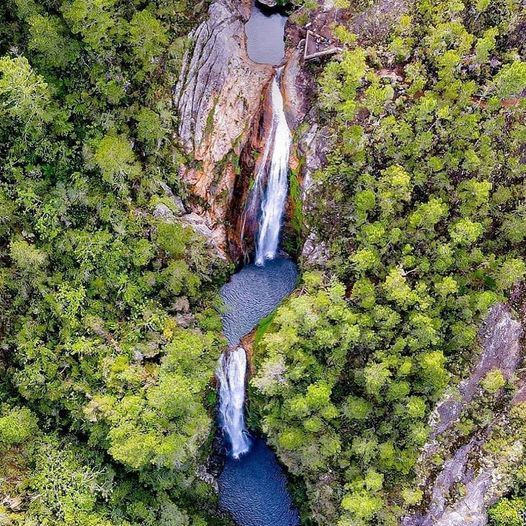 Una vista aérea de una cascada en medio de un bosque rodeado de árboles.