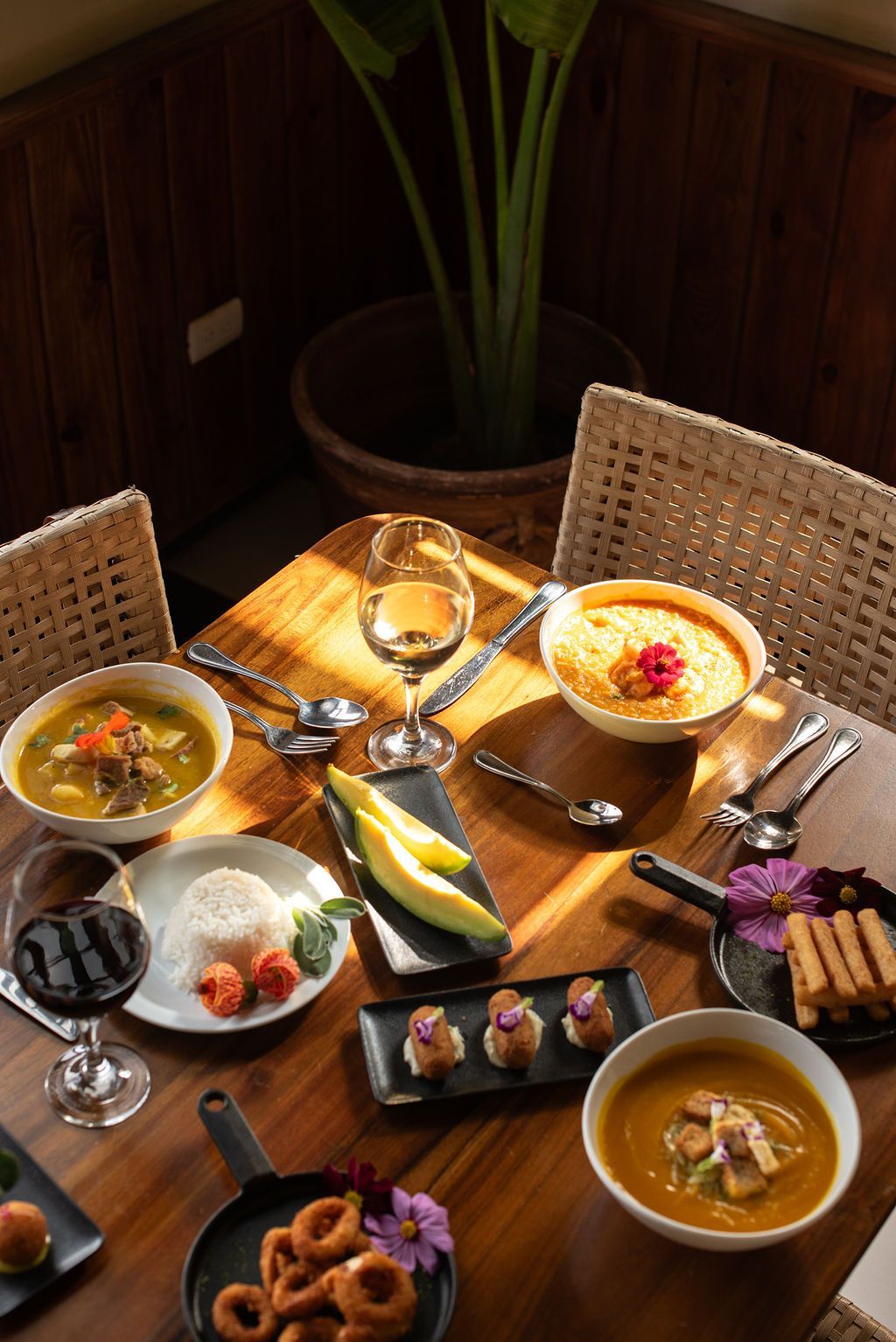 Una mesa de madera cubierta con cuencos de comida y copas de vino.