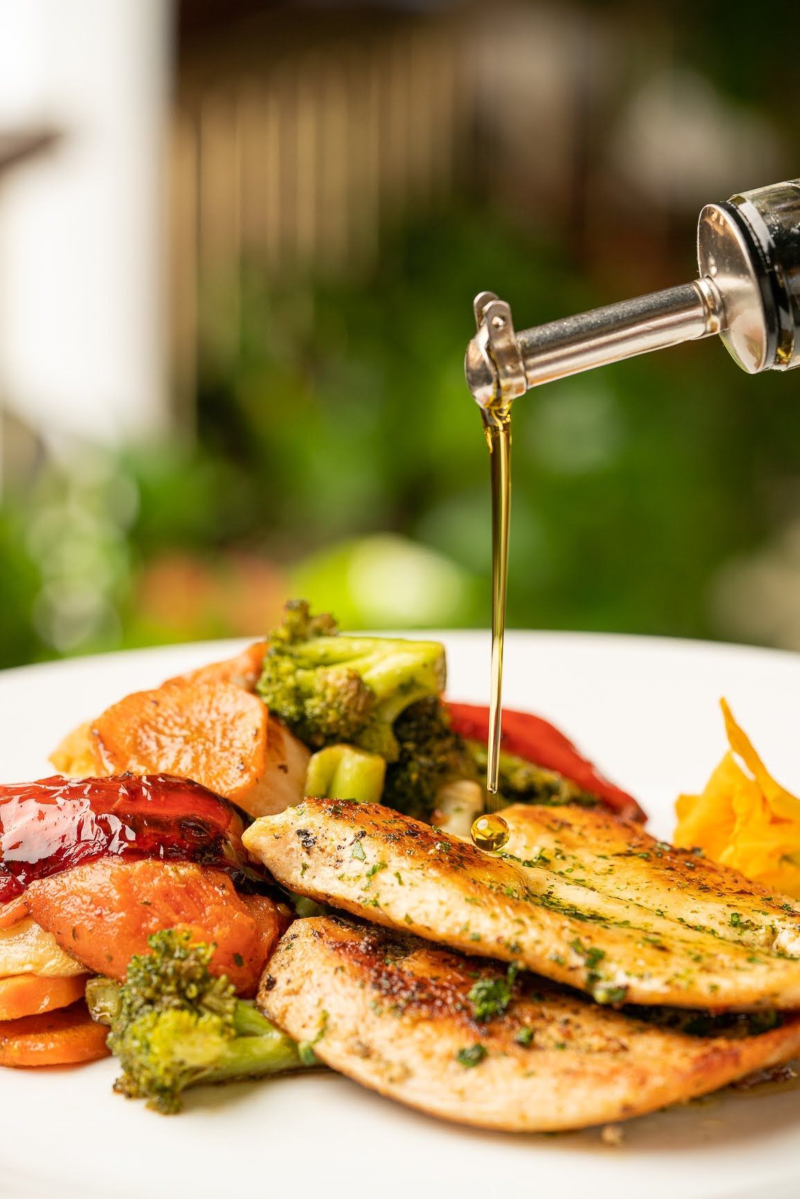 Un primer plano de un plato de comida con pollo y verduras vertido con aceite.