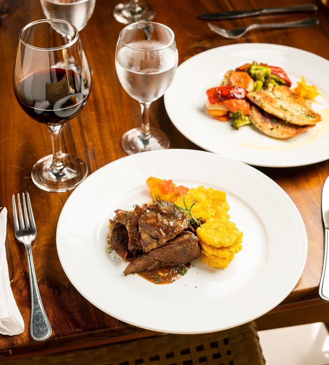 Dos platos de comida y dos copas de vino sobre una mesa