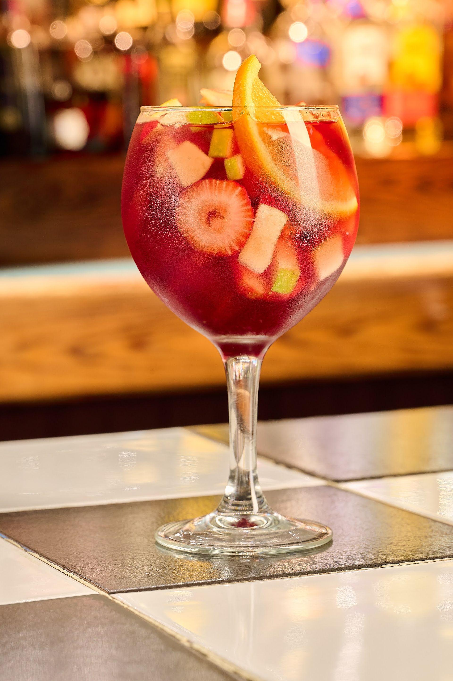 Un vaso de sangría con fresas y naranjas sobre una mesa.