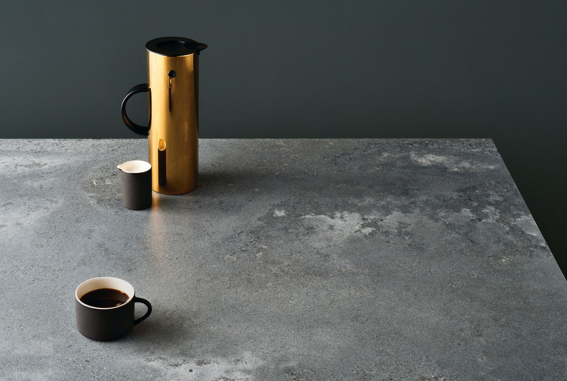 Gold carafe, black cup, and a smaller black cup on a mottled gray countertop — Lukas Joinery in Belmont, NSW