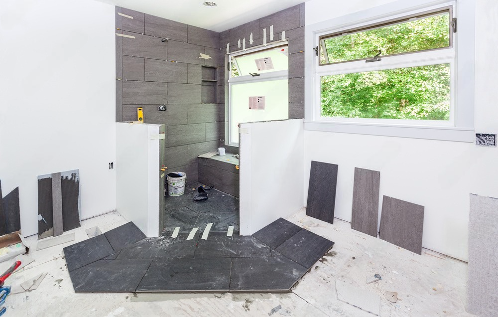 A bathroom under construction with tiles on the floor and a window.