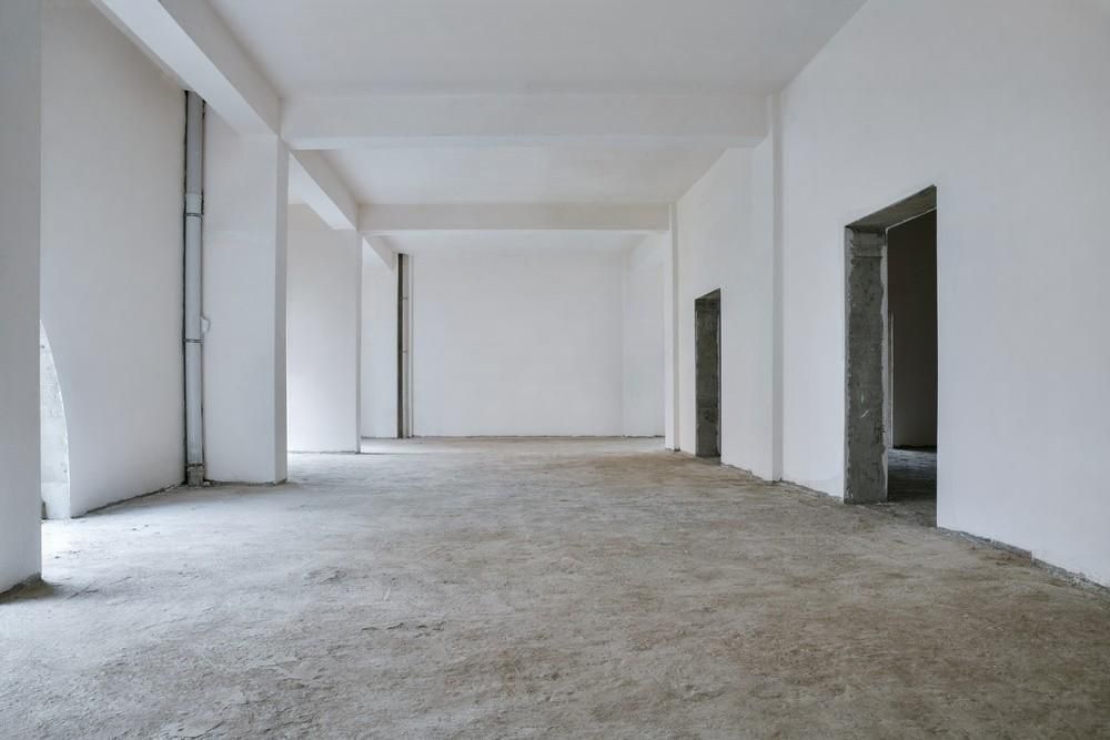 A large empty room with concrete floors and white walls.
