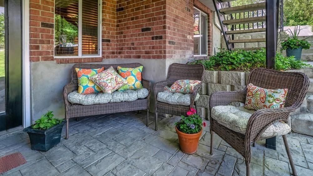 A patio with a couch , chairs , and potted plants.