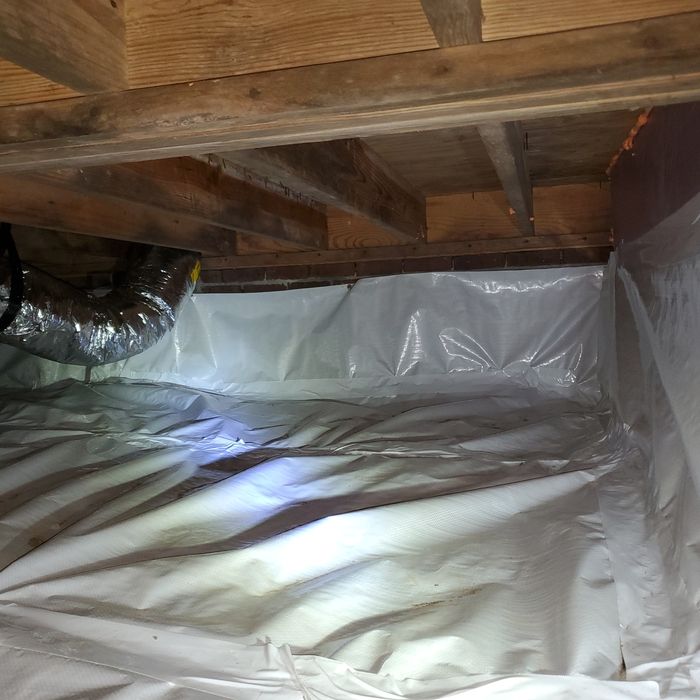 Crawl space with white plastic sheeting covering the dirt floor and walls, ductwork, and wooden beams above.