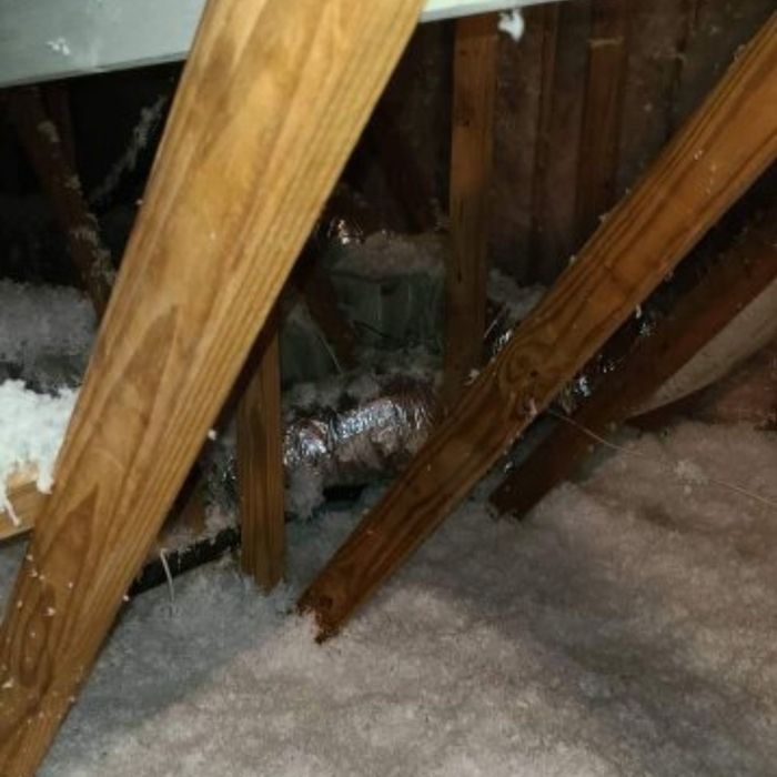 Attic interior with wood beams, insulation, and ductwork.
