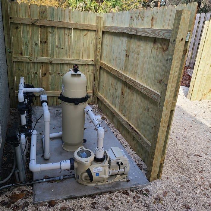 Pool pump and filter system enclosed by wooden fence.