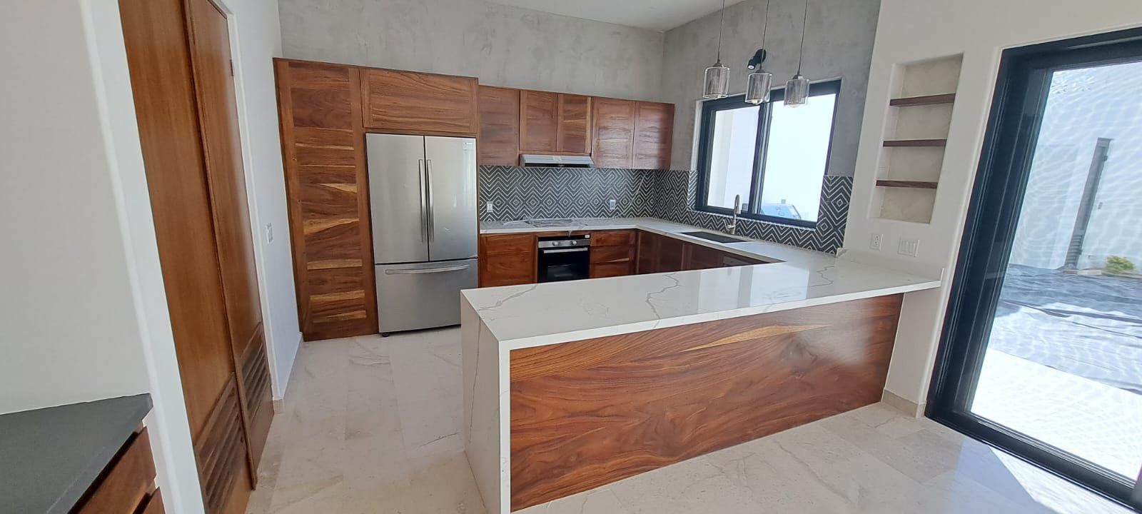 Una cocina con gabinetes de madera, electrodomésticos de acero inoxidable, refrigerador y fregadero.