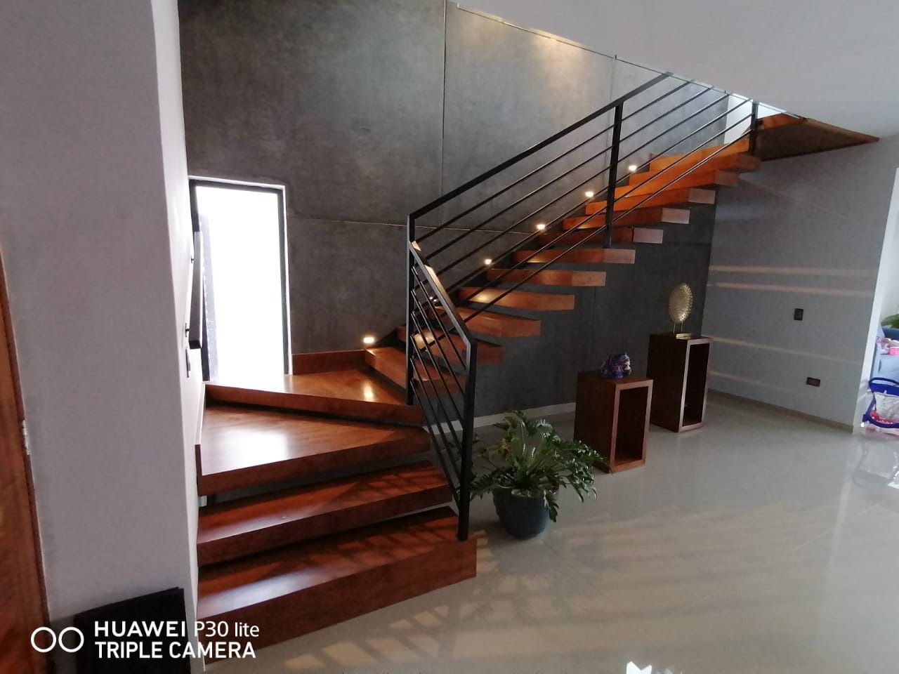 Una escalera de madera con barandilla metálica en una casa.