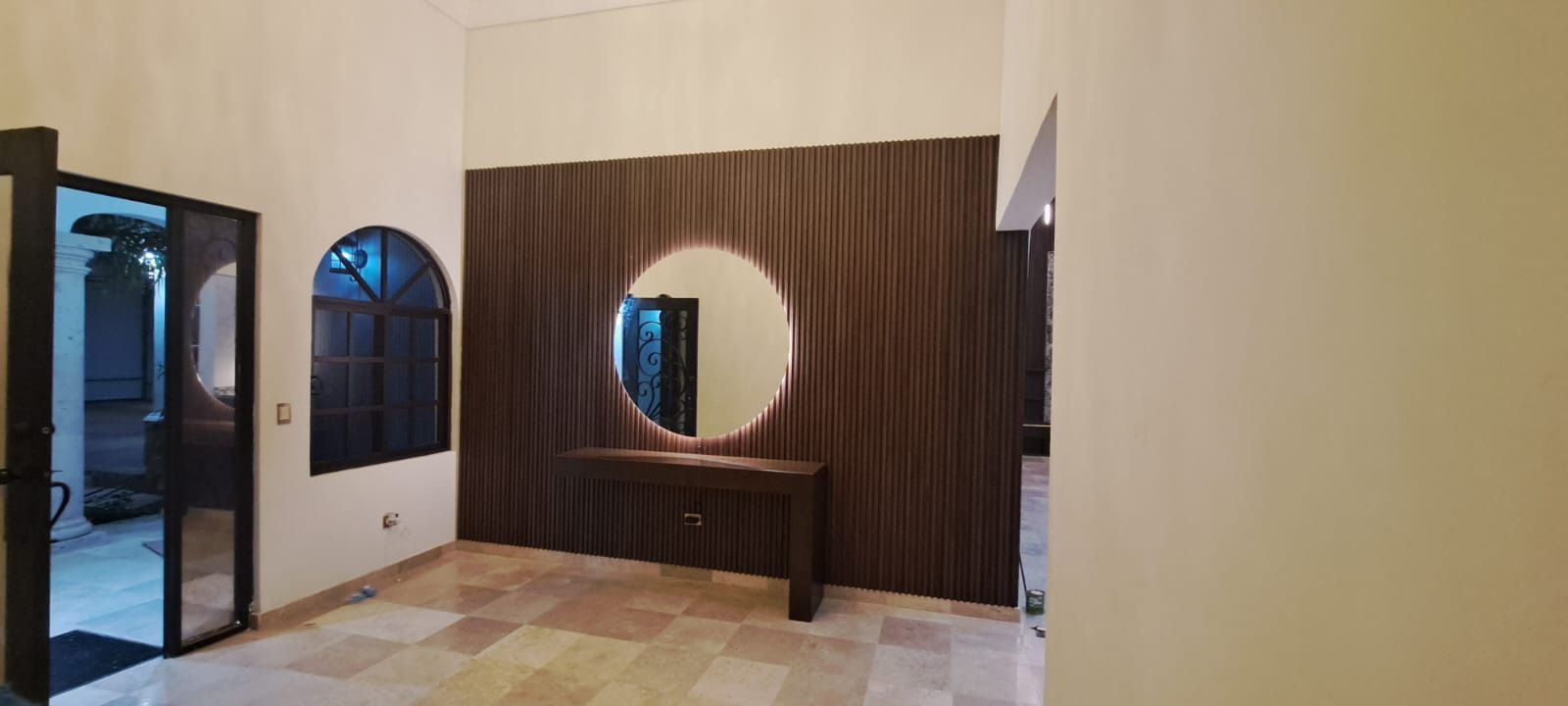 Una gran sala vacía con una mesa y un espejo en la pared.