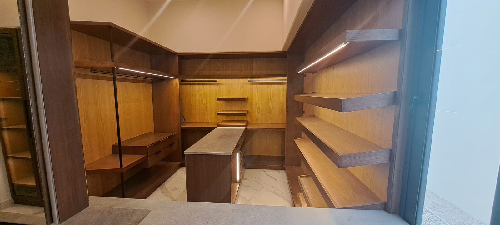 Un vestidor con estantes de madera y un espejo.