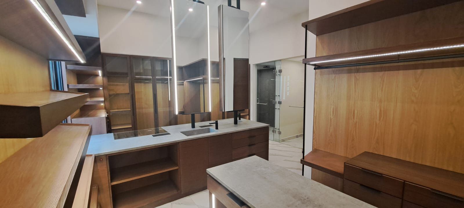 Un vestidor con lavabo, espejos y estantes.