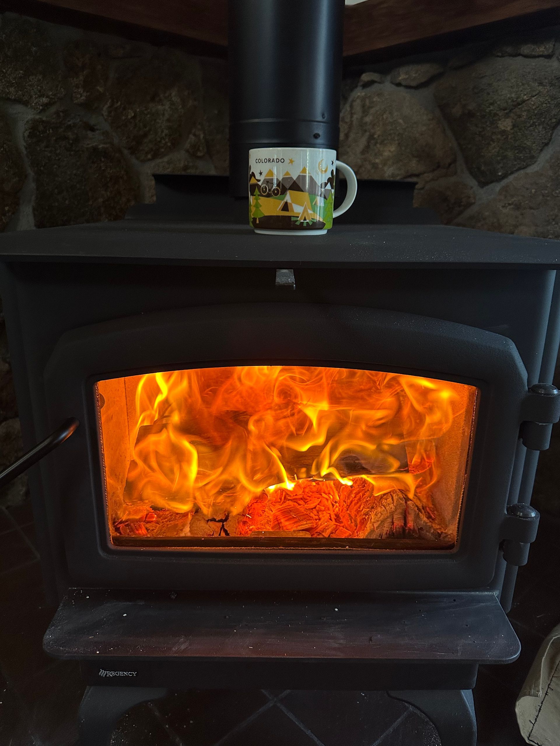 A wood stove with a mug on top of it