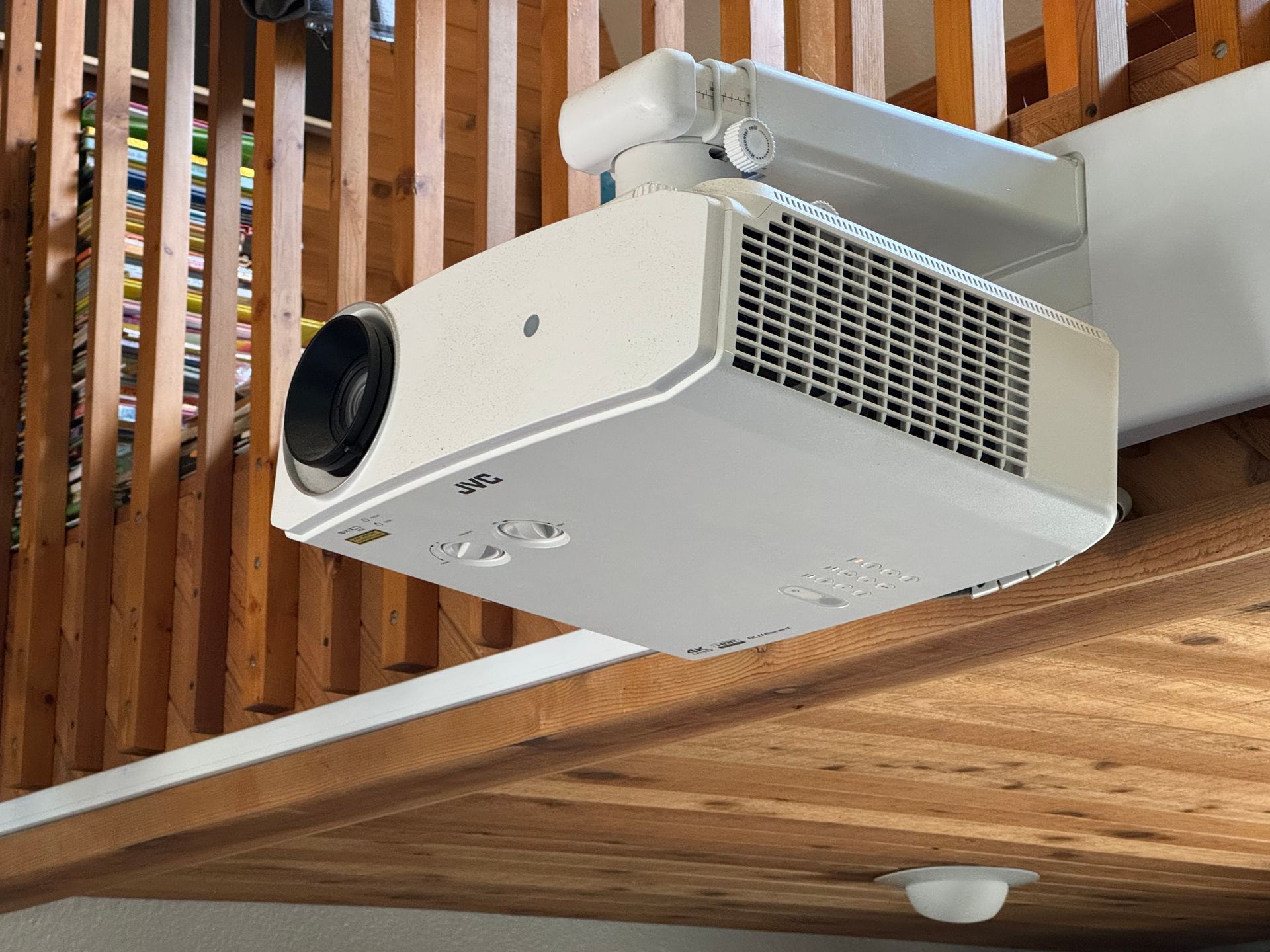 A white projector is hanging from the ceiling of a room.