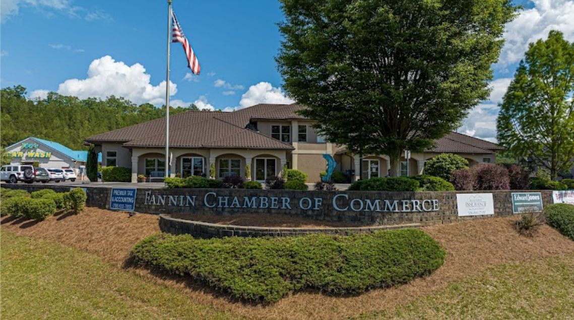 The Fanin Chamber of Commerce building with a large sign, US flag, and blue sky.