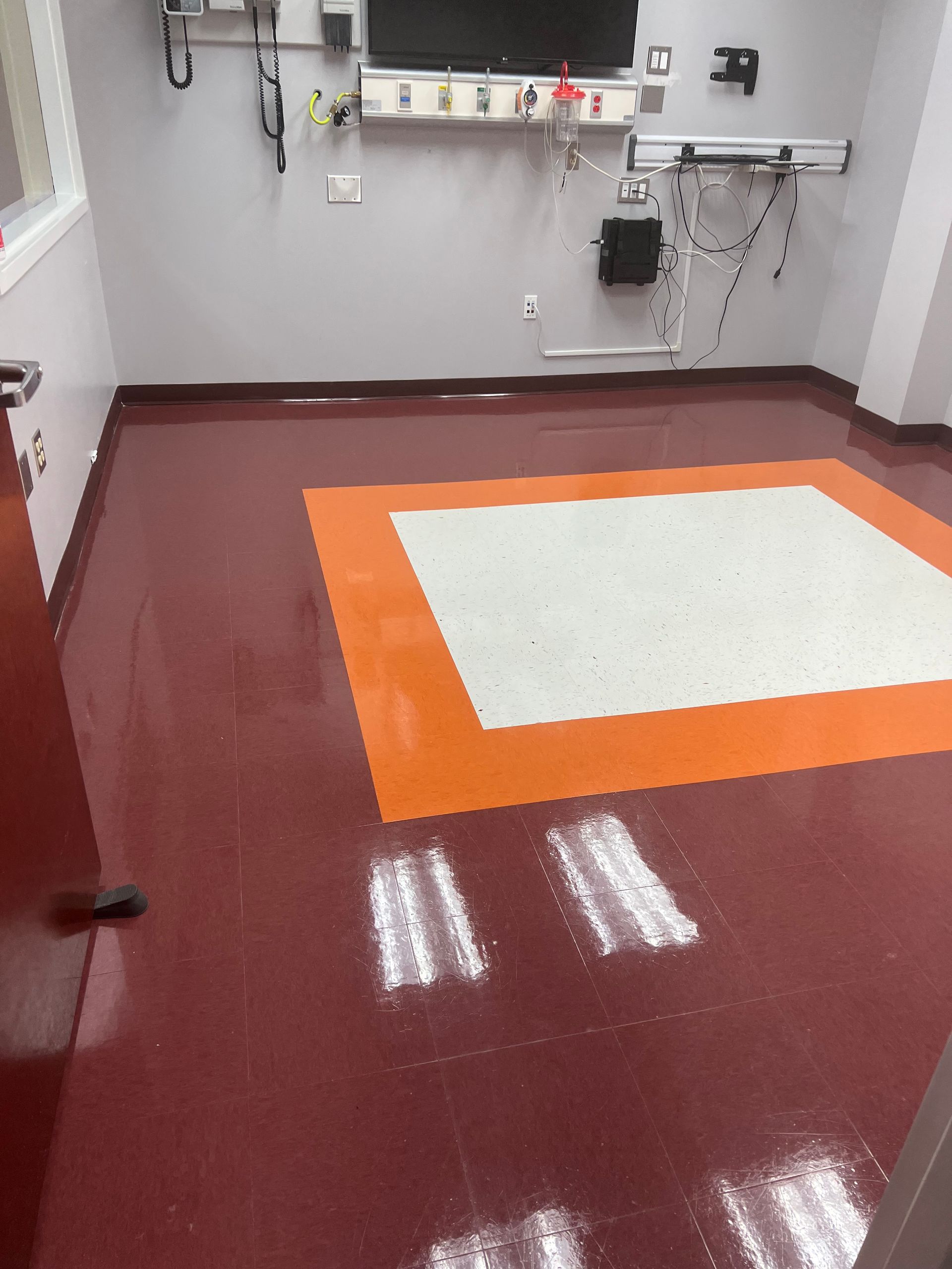 A room with a red floor and a white and orange rug.