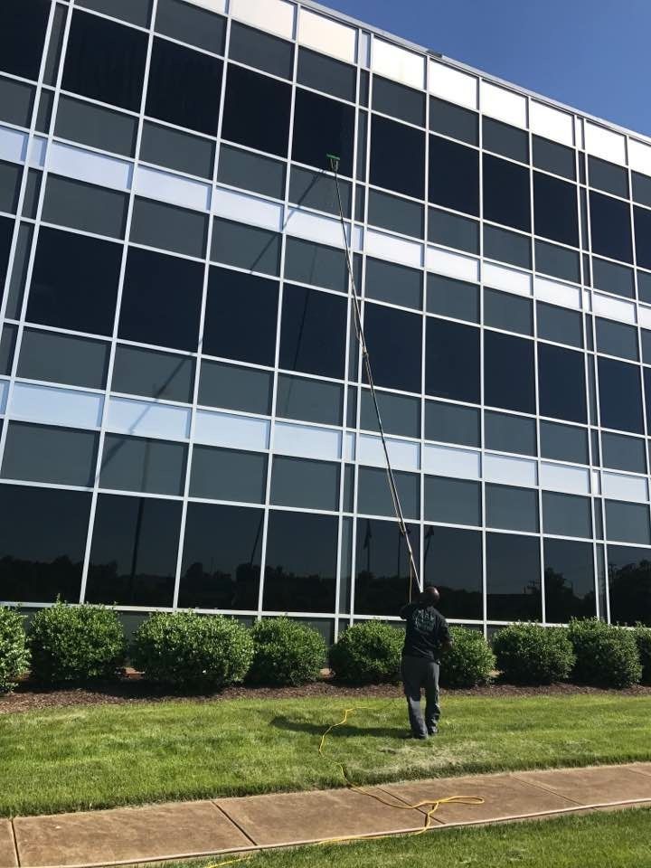 A man is cleaning the outside windows of a large building.