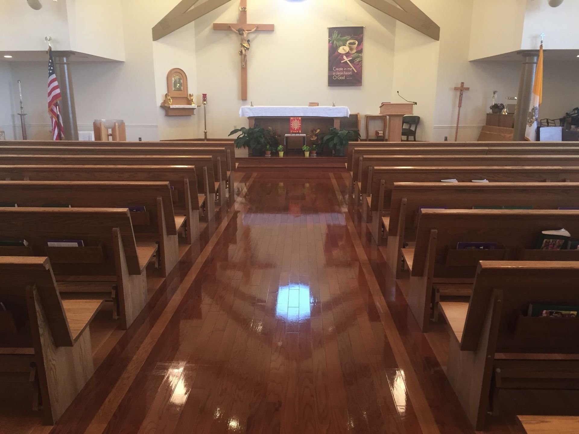A church with rows of wooden benches and a cross on the altar.