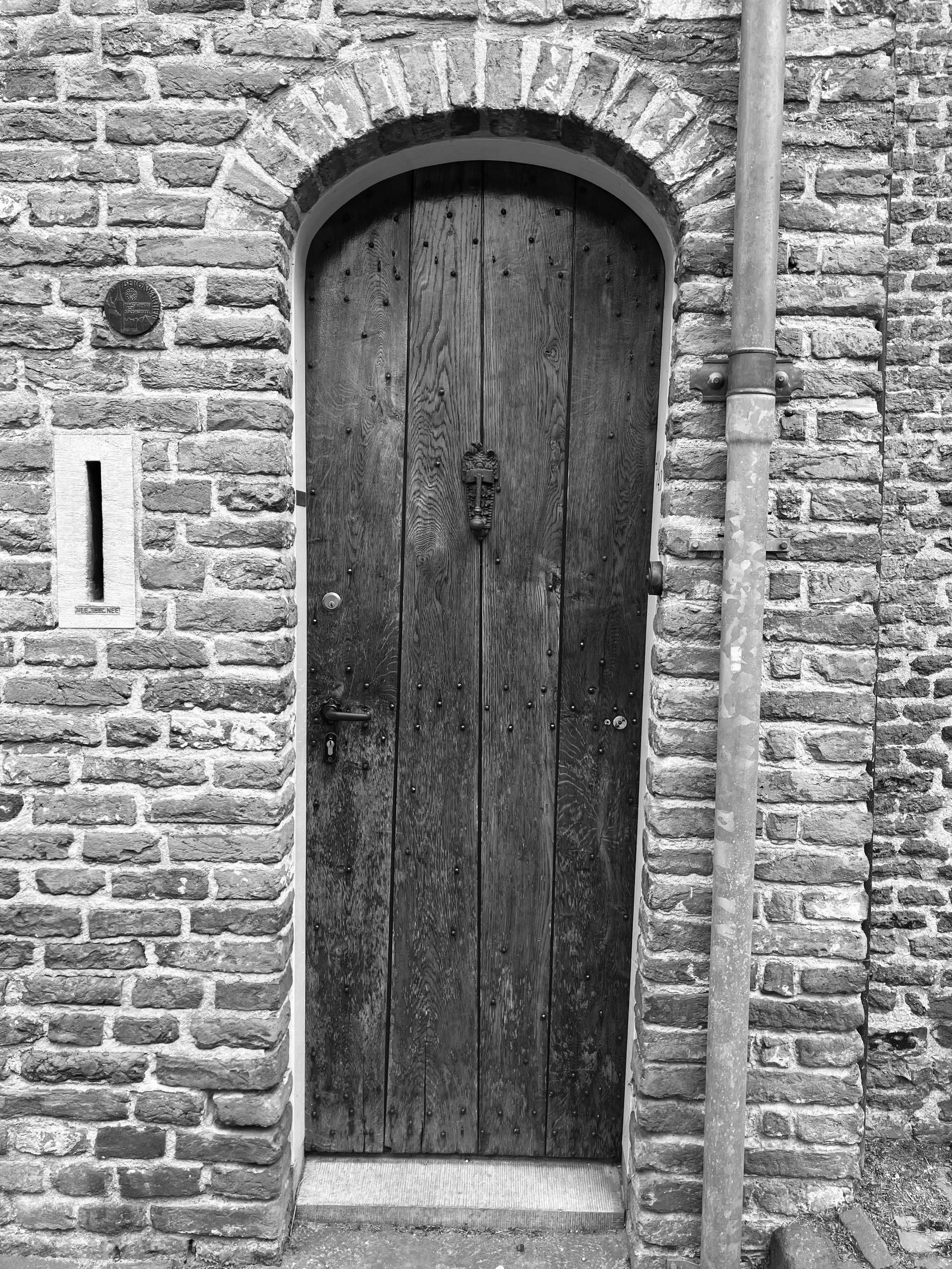 Houten deur met gebogen bakstenen kozijn in een bakstenen muur.