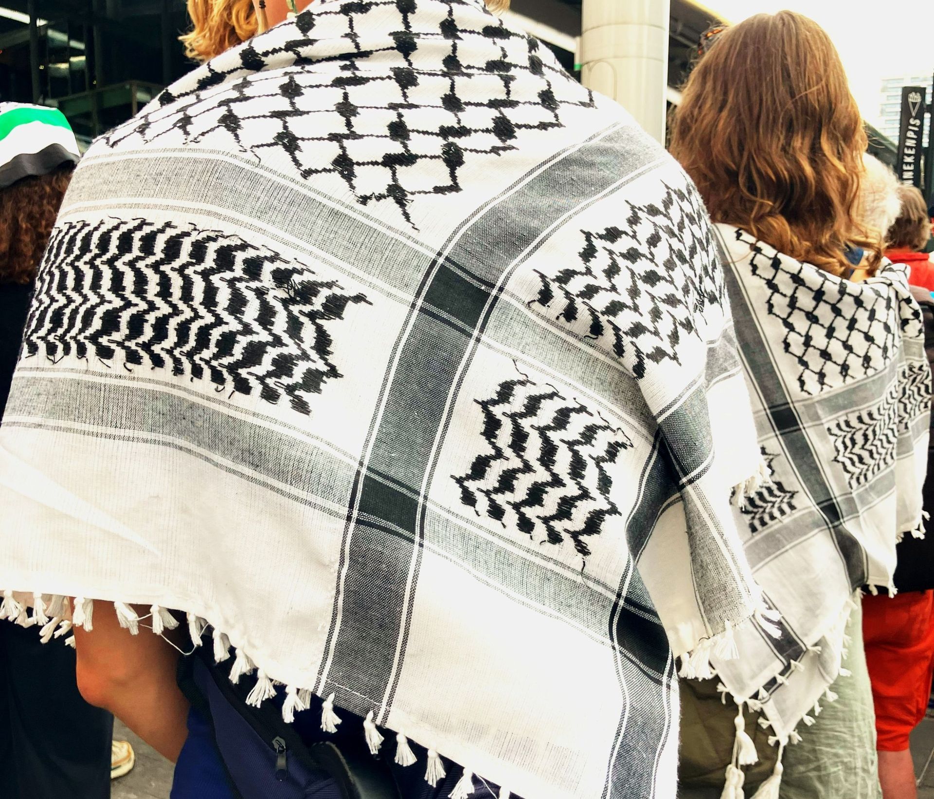 Protest op een treinstation; menigte zit op de grond en zwaait met Palestijnse vlaggen.