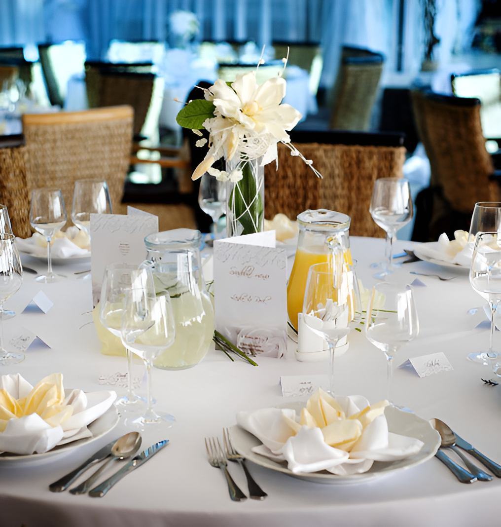 Elegant table setting with white tablecloth, flowers, juice, and glassware.