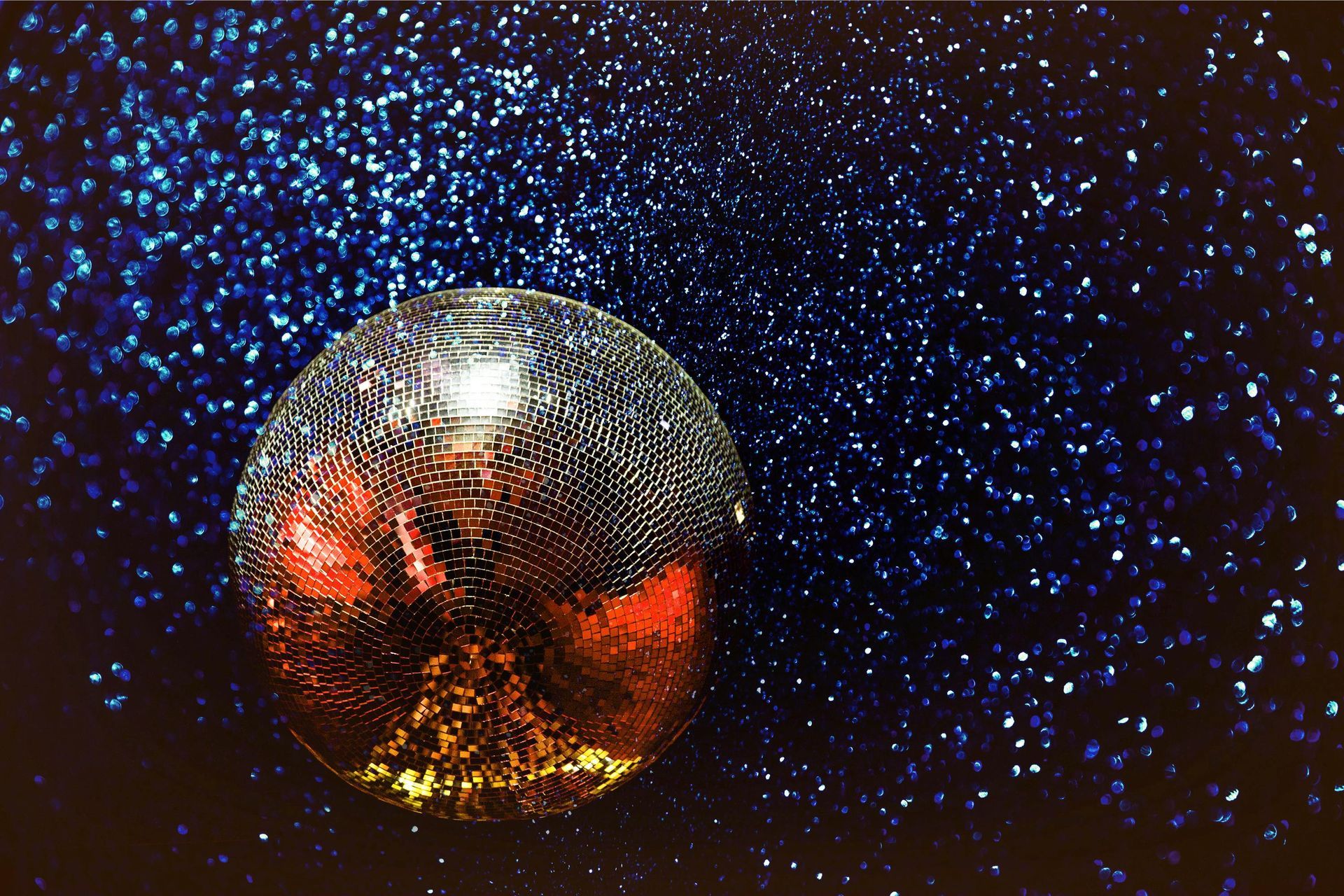 Ornate glass sphere reflecting red and yellow light, set against a sparkling blue backdrop.