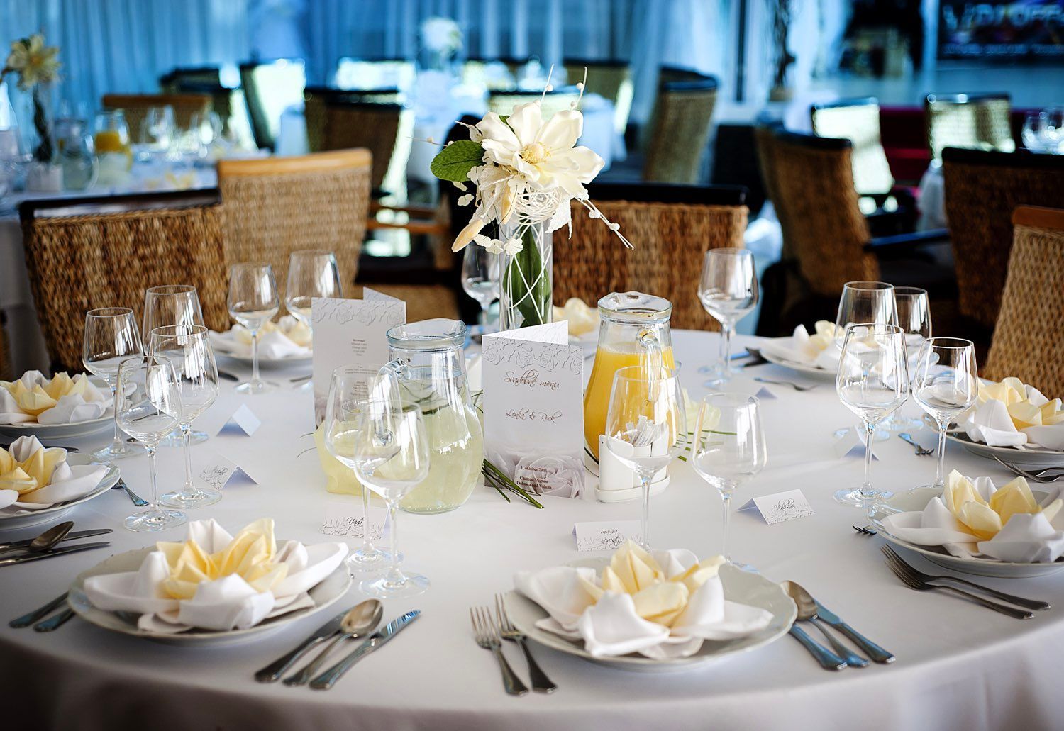 Elegant round table set for a wedding, with white linens, floral centerpieces, and place settings.