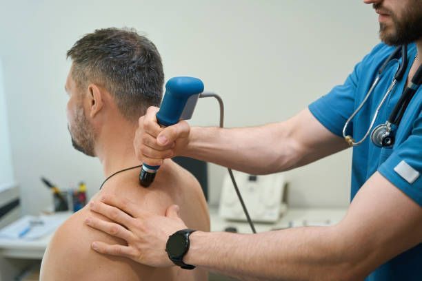 Patient receiving shockwave therapy for pain relief on the back in a professional medical setting.