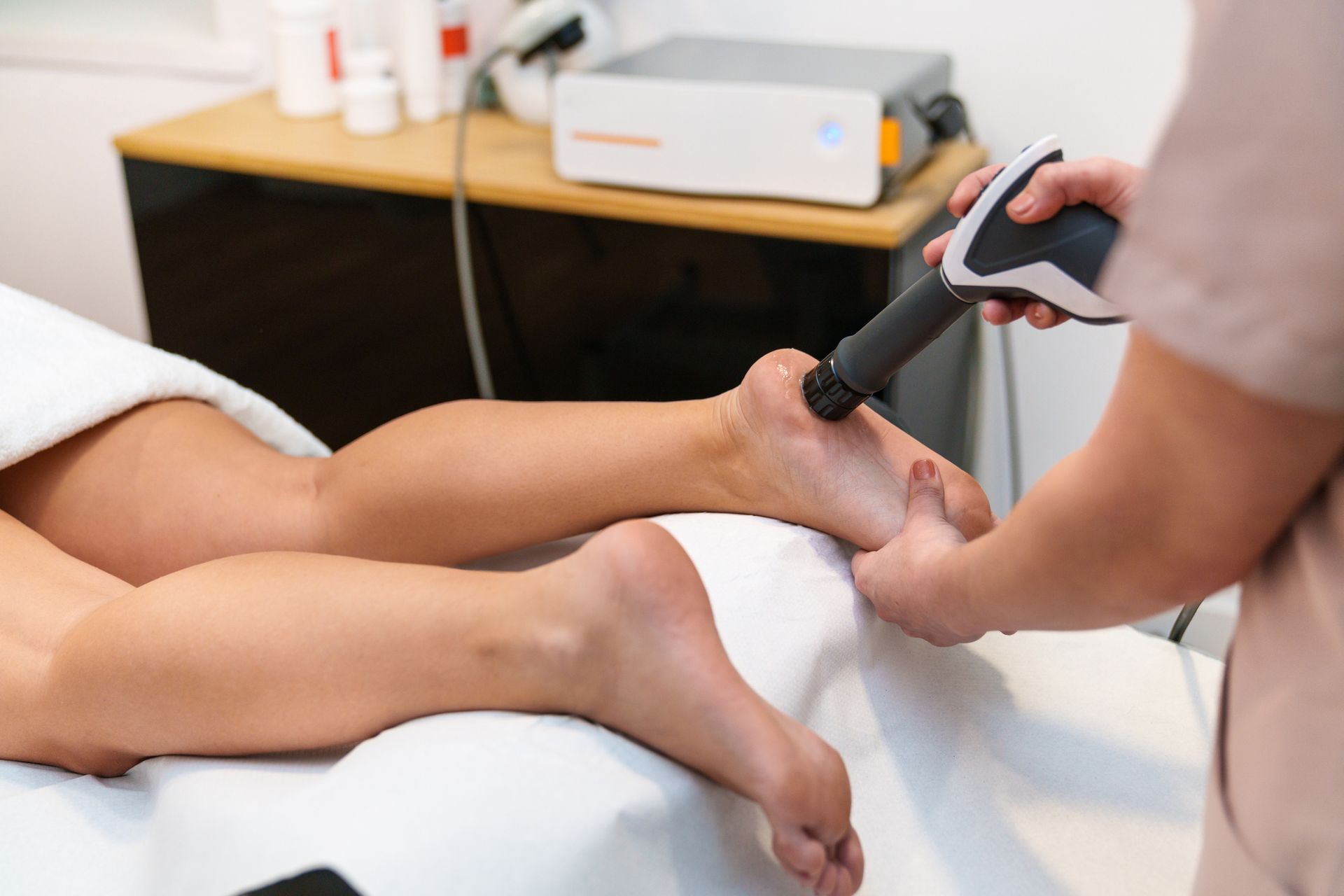 Therapist using device for shockwave therapy for slip and fall injuries on foot. Therapist using device for shockwave therapy for slip and fall injuries on foot.