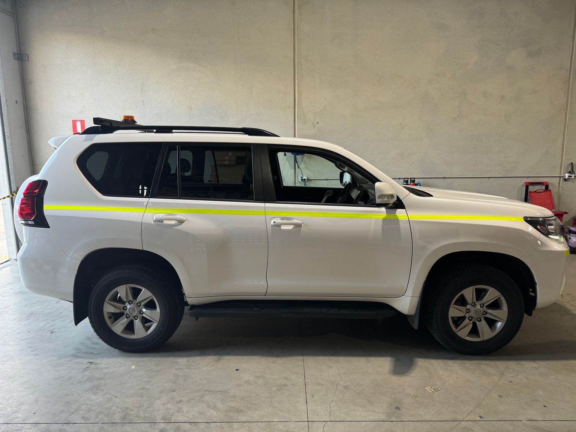 White Toyota Landcruiser with yellow stripes, parked in a garage.