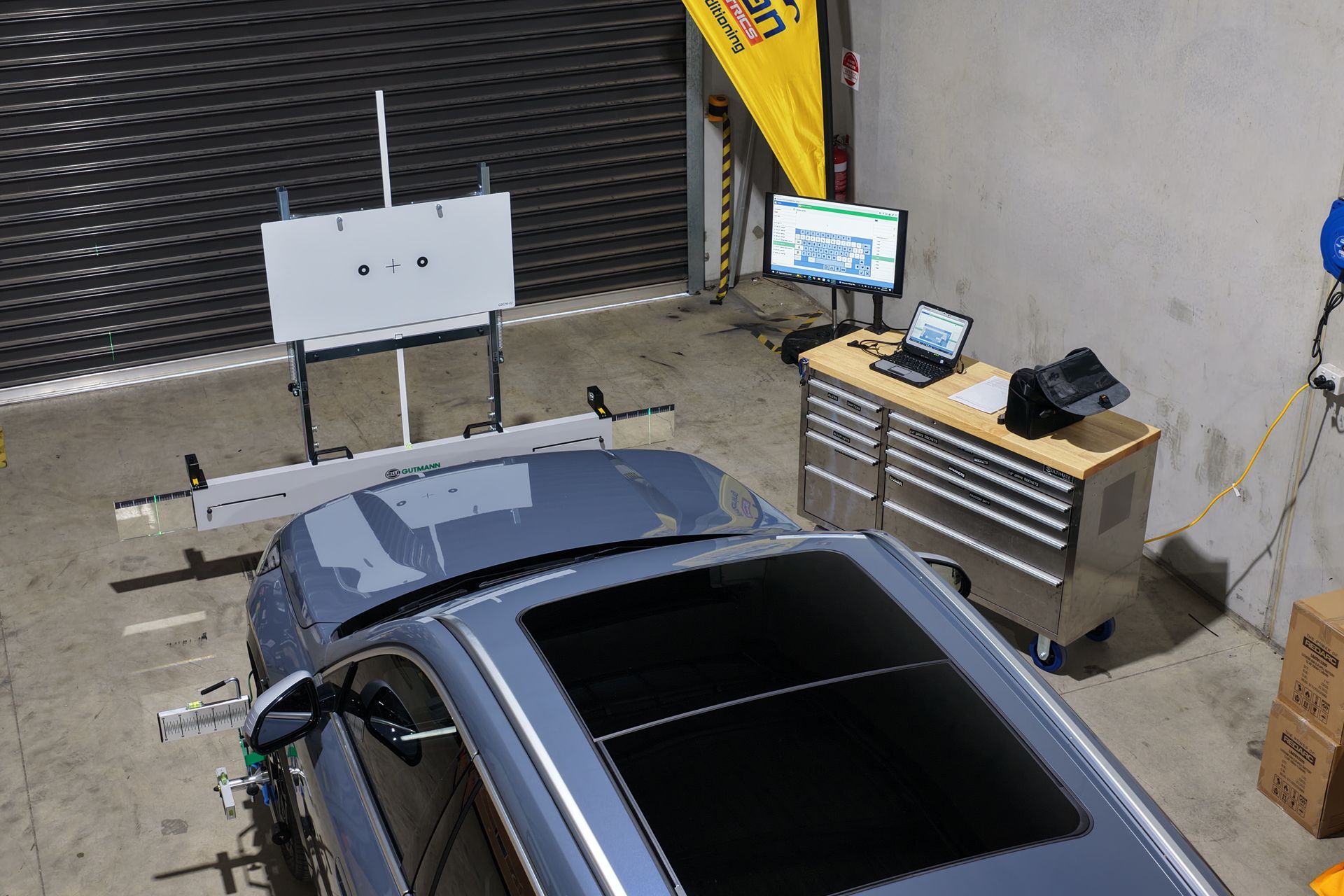 Car being aligned in a workshop, with alignment equipment set up around it.