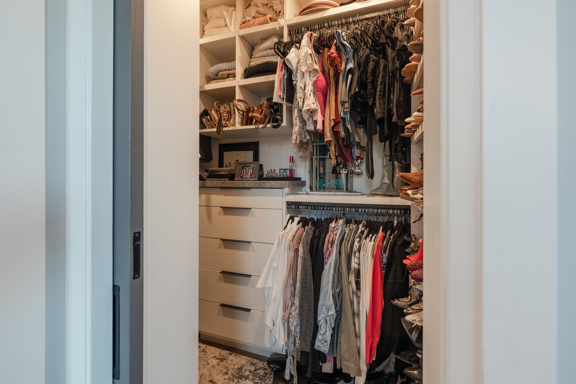 A walk in closet filled with lots of clothes and shoes.