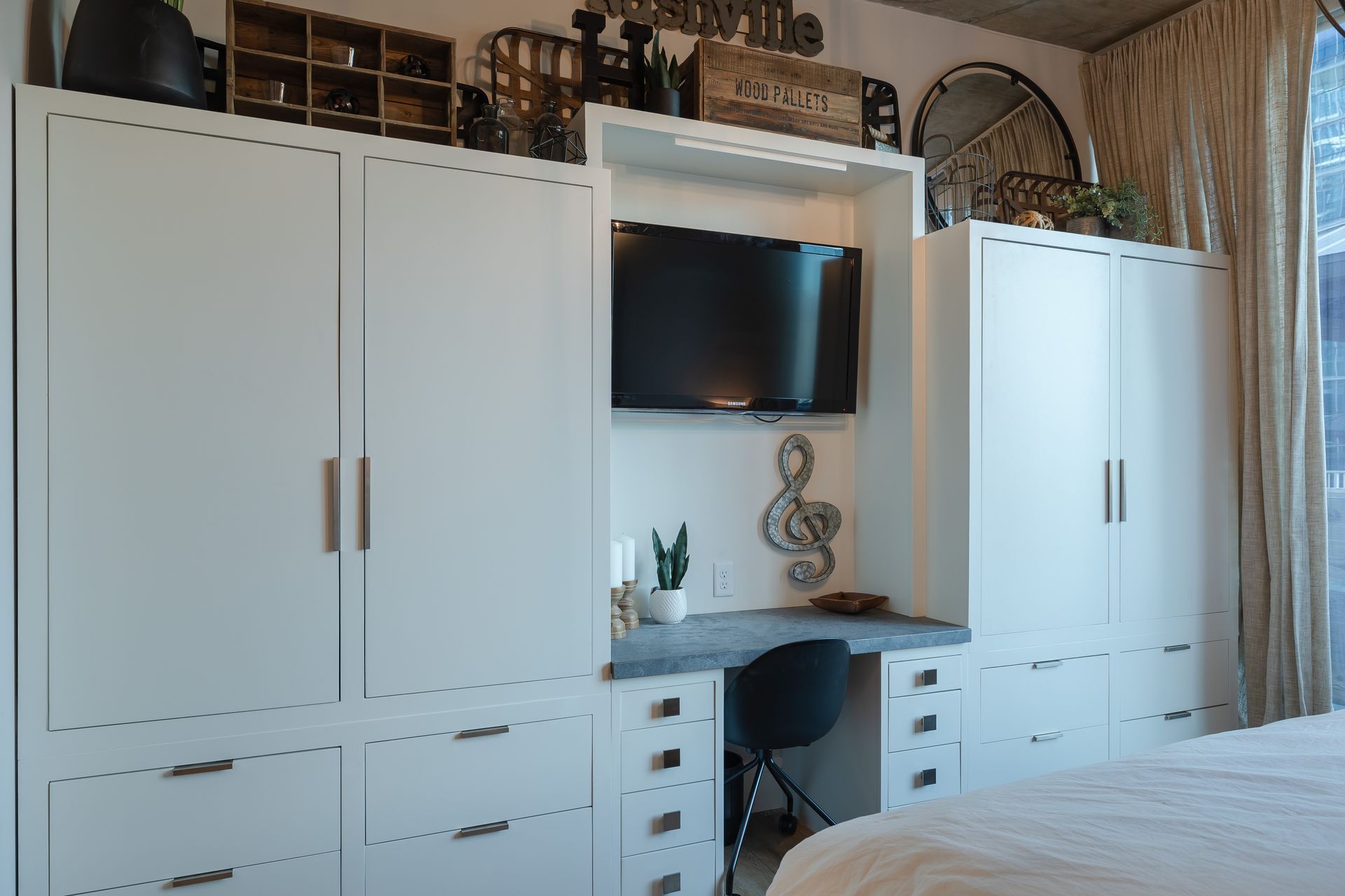 A bedroom with a desk and a flat screen tv on the wall.