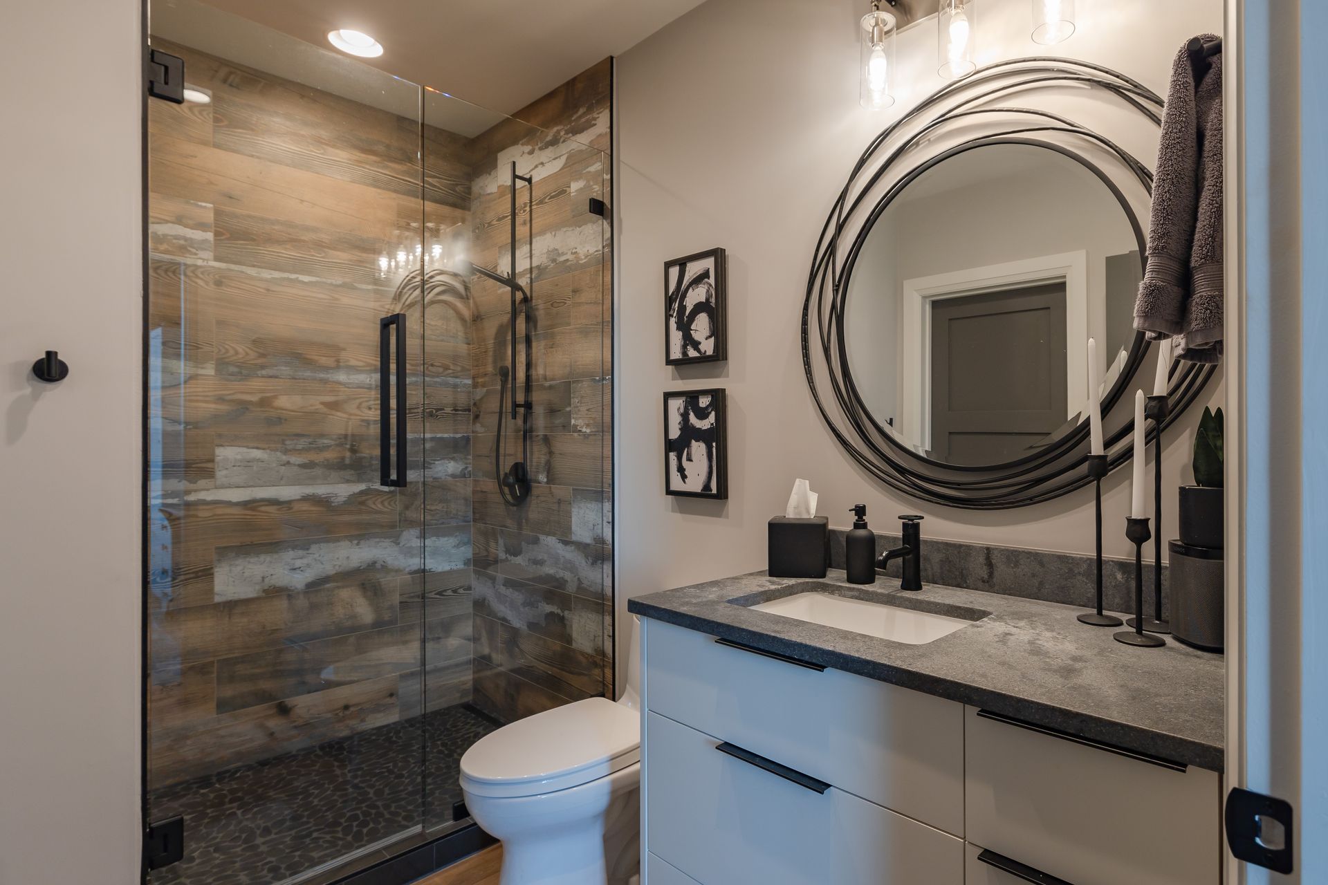 A bathroom with a toilet , sink , mirror and walk in shower.