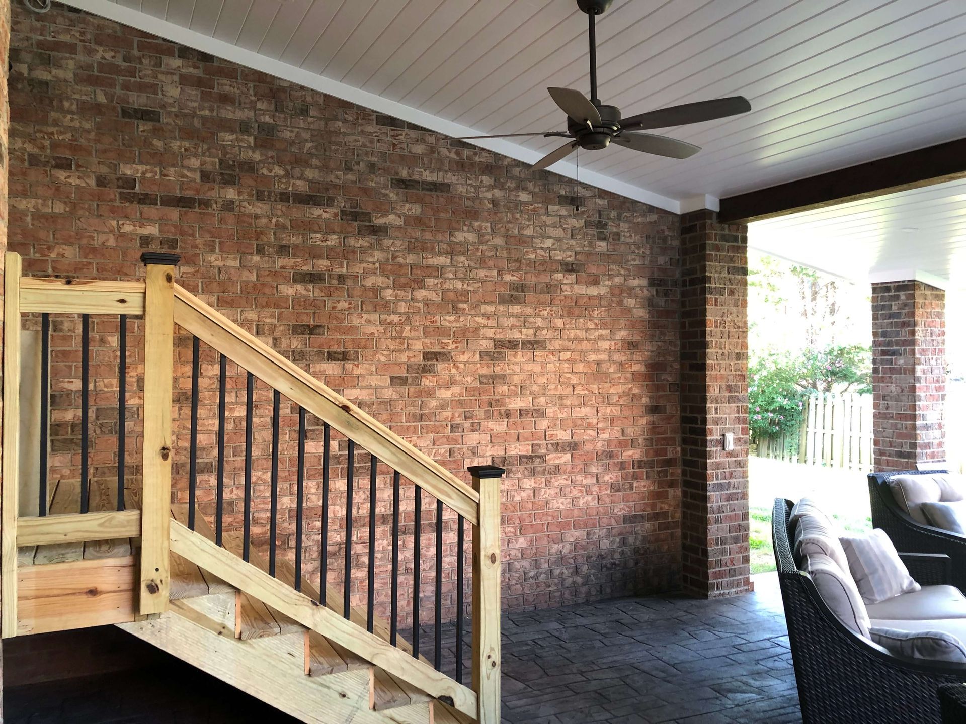 A wooden staircase leading up to a porch with a ceiling fan.