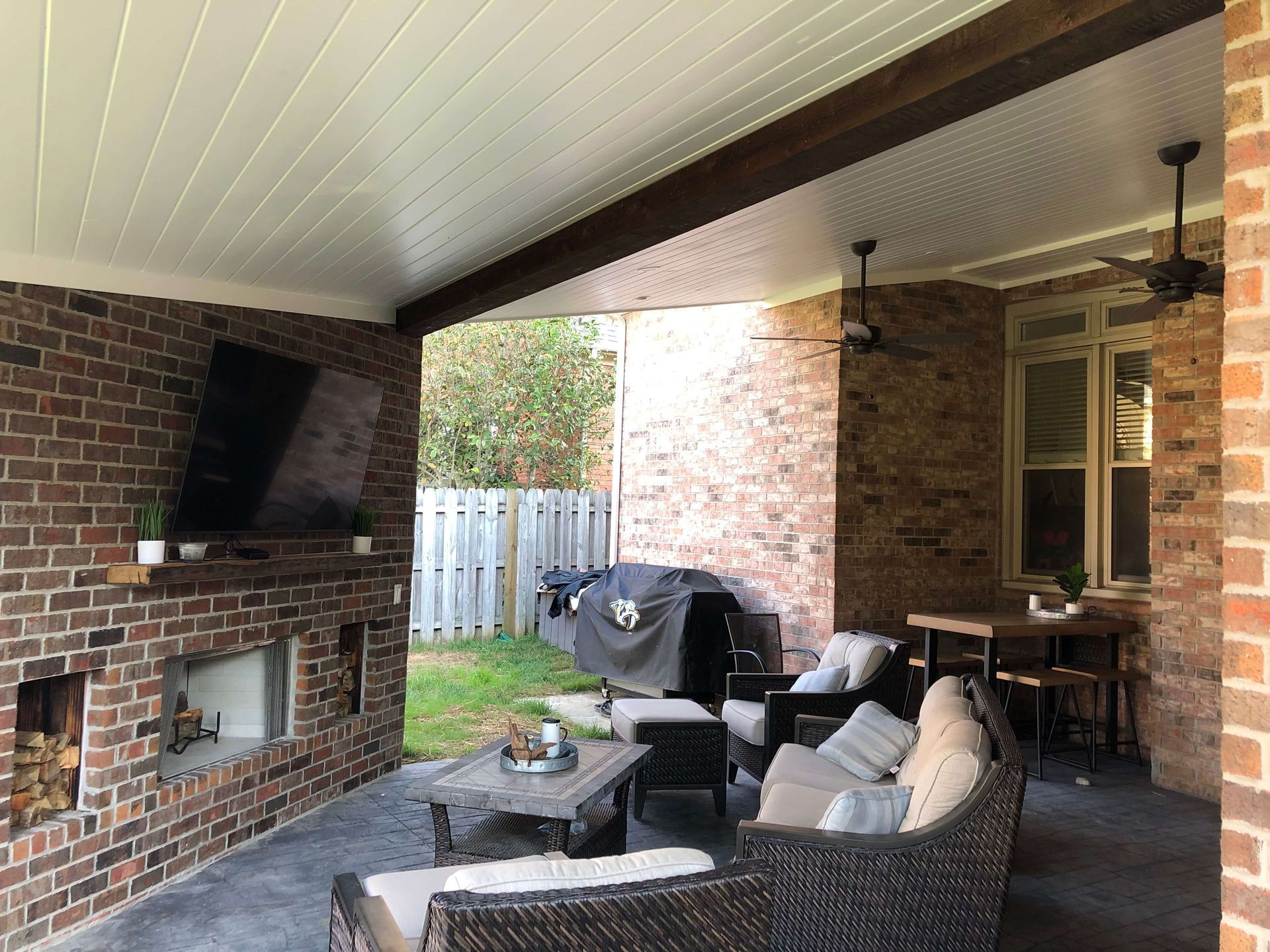 A patio with a couch , chairs , table and television.