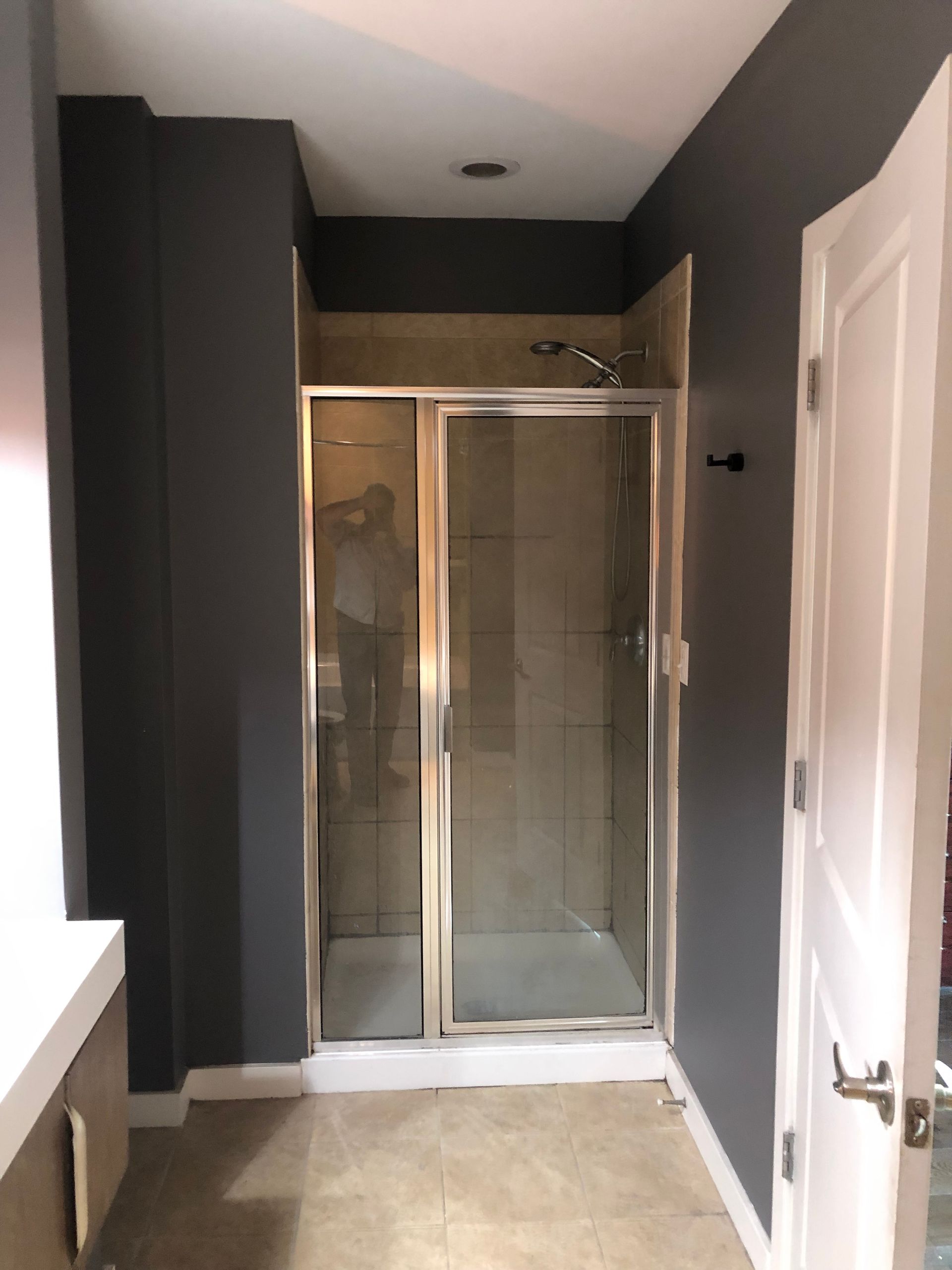 A bathroom with a walk in shower and gray walls