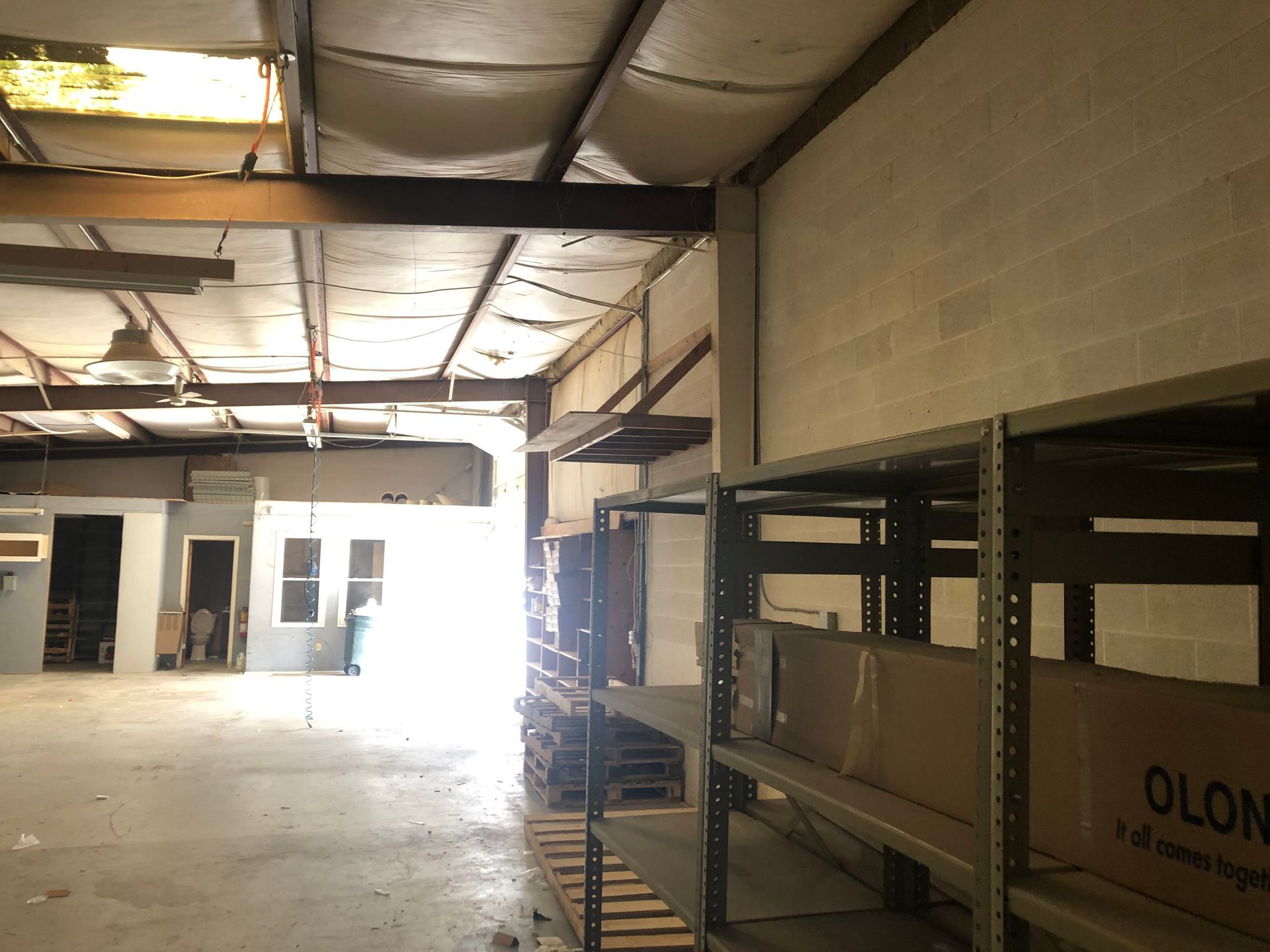 An empty warehouse with shelves and a box that says olcon on it