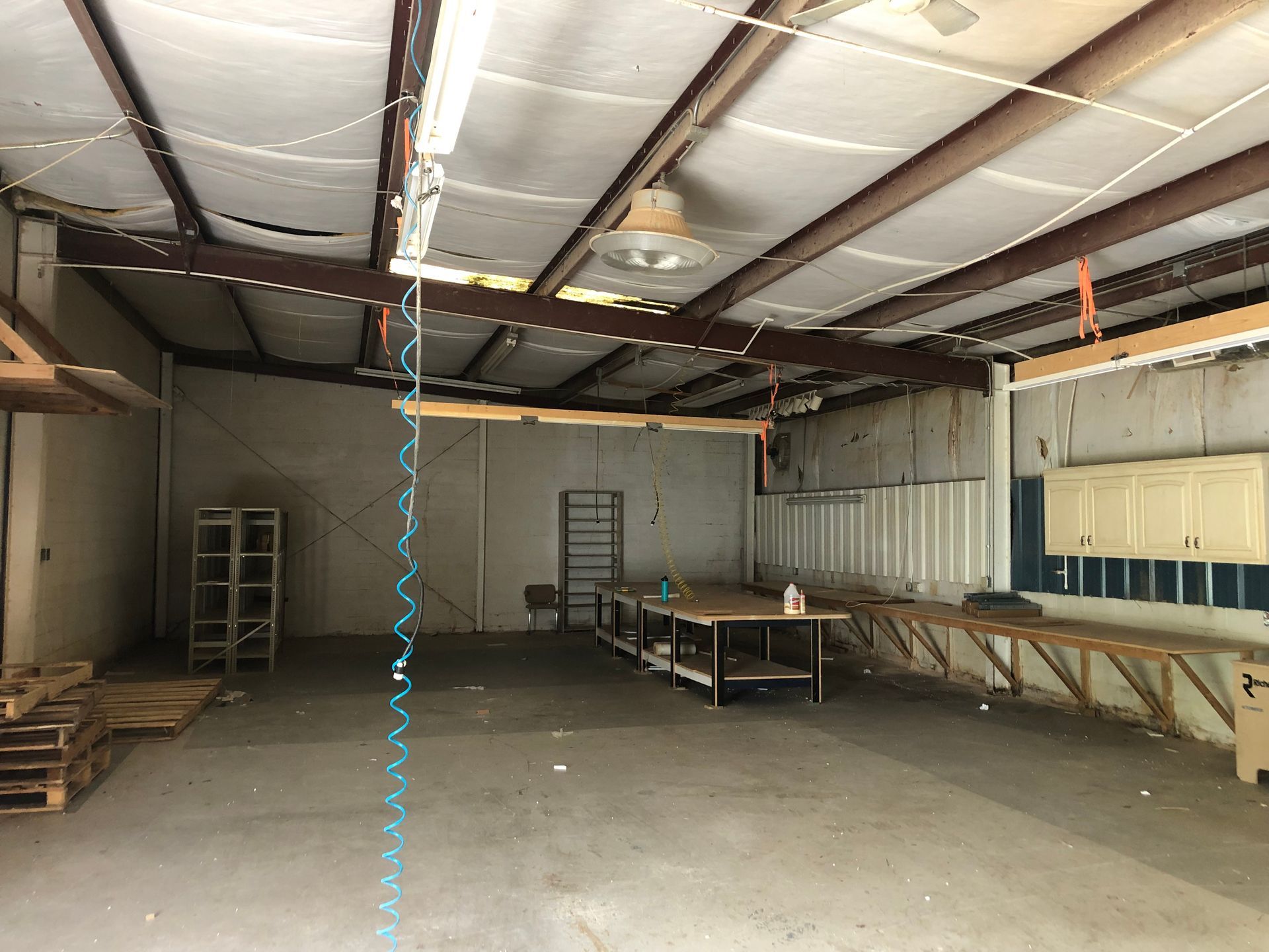 A large empty room with a ceiling fan hanging from it.