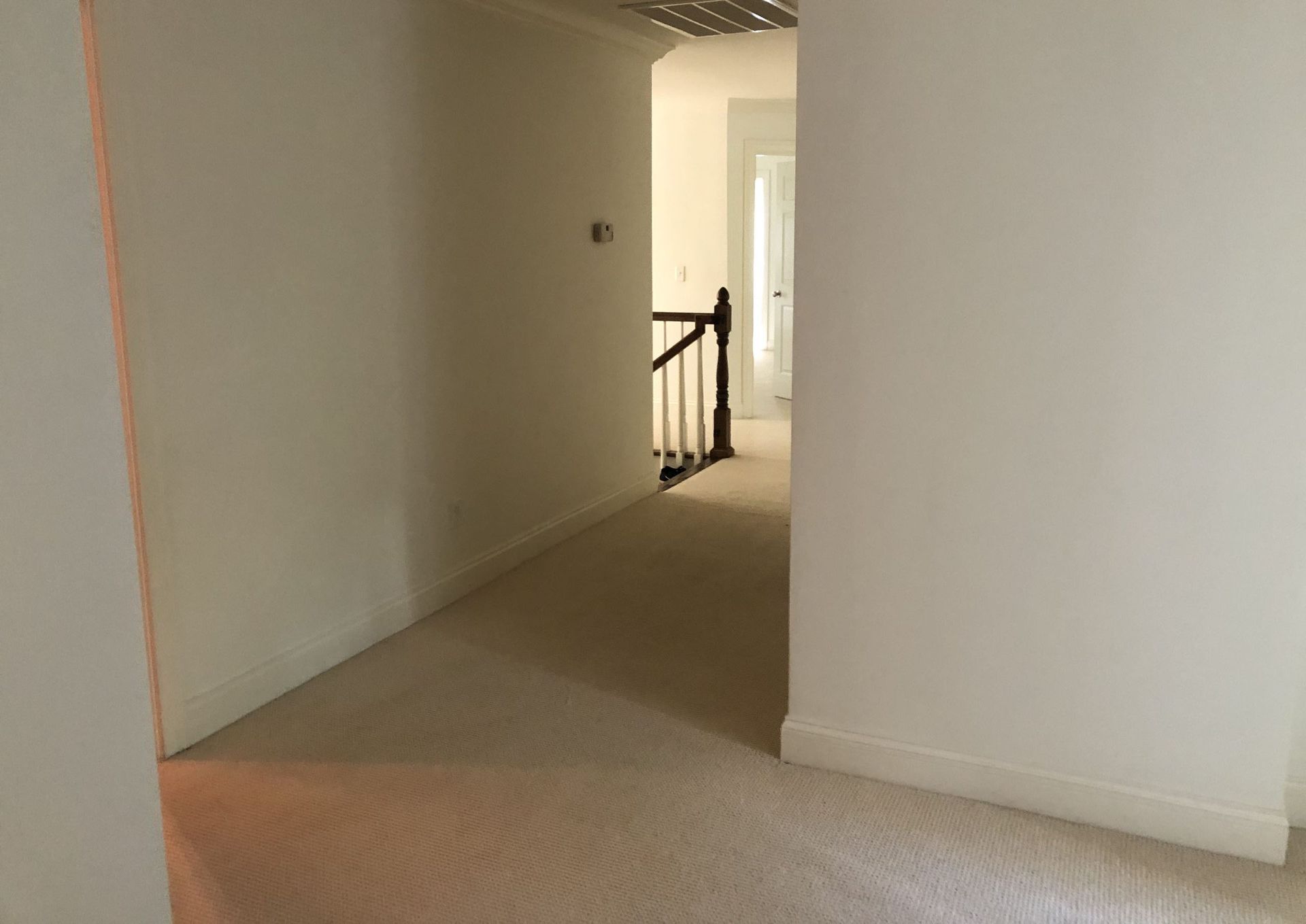 An empty hallway with a wooden staircase in a house.