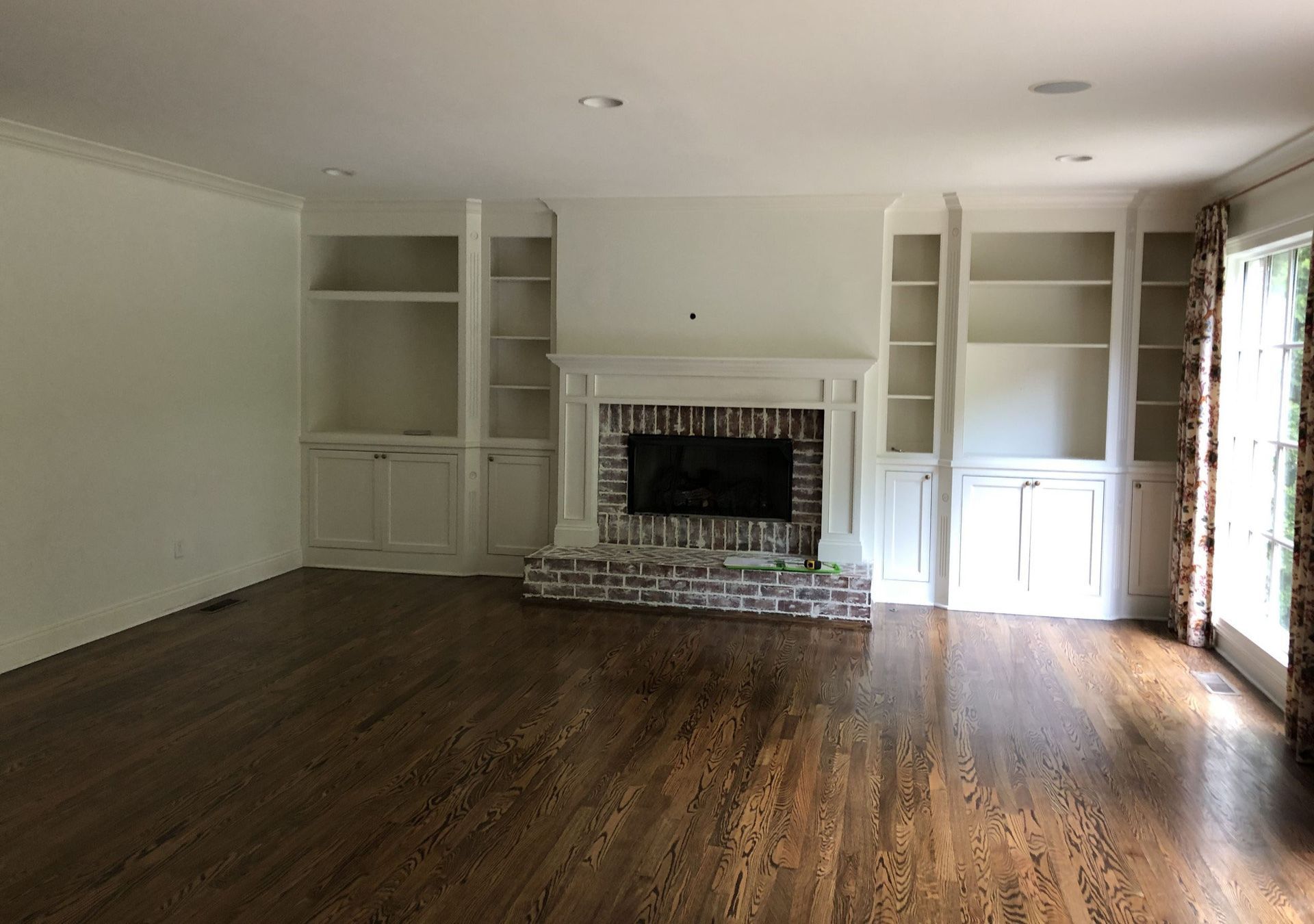 An empty living room with hardwood floors and a fireplace.