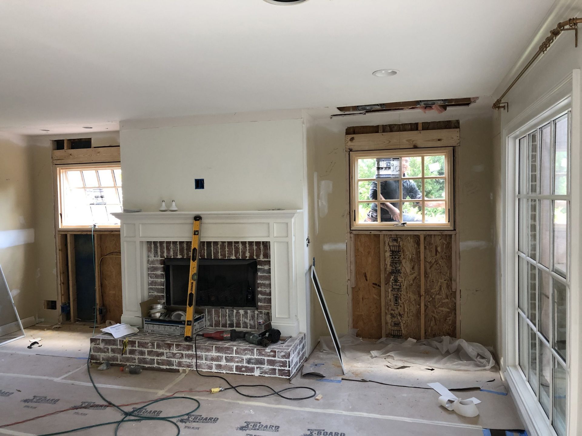 A living room with a fireplace and a window under construction