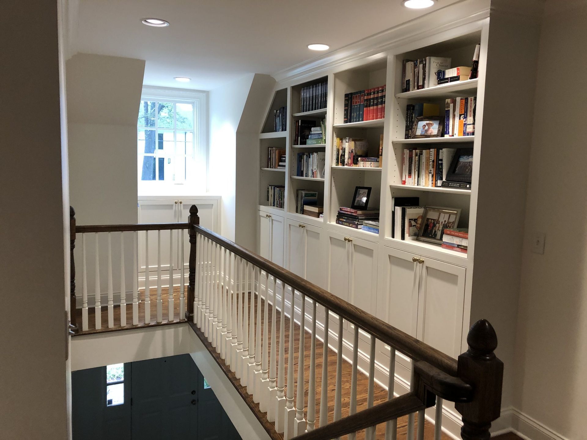A hallway with a railing and shelves filled with books.